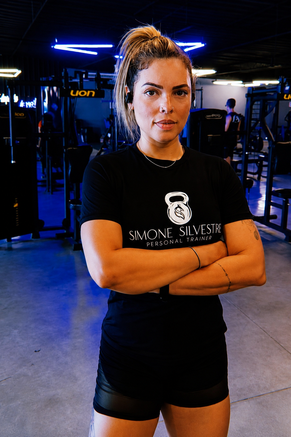 Simone Silvestre, personal trainer, em pé de braços cruzados no estúdio de treino